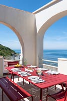 Table à manger extérieure dressée pour le déjeuner sur une terrasse fortifiée avec vue sur la mer