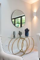 Table inhabituelle avec des ornements sous un miroir circulaire et une applique