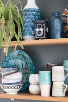 Étagères en bois avec vaisselle bleu et blanc et articles de poterie contre mur gris foncé