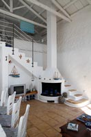 Cottage de style méditerranéen à aire ouverte, salon et salle à manger avec cheminée sous les escaliers