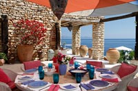 Table à manger extérieure ronde posée pour le déjeuner sur une terrasse couverte avec vue sur la mer