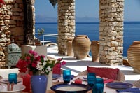 Table à manger extérieure dressée pour le déjeuner sur une terrasse couverte avec vue sur la mer