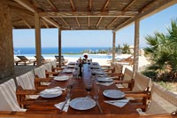 Grande salle à manger extérieure sur terrasse couverte avec vue sur la piscine et la mer au-delà