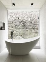 Baignoire autoportante à côté d'une grande baie vitrée dans une salle de bains contemporaine
