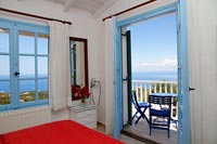 Chambre de campagne méditerranéenne avec portes-fenêtres ouvertes sur balcon avec vue sur la mer