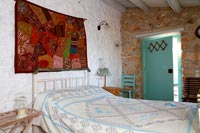 Chambre de campagne avec tenture murale en tissu coloré au-dessus du lit
