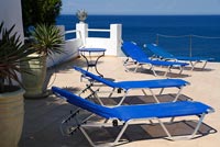 Fauteuils inclinables bleus sur terrasse donnant sur la mer