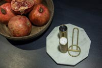 Grenades dans un bol à côté de plateau en marbre de condiments sur table à manger