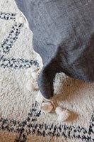 Détail de coussin gris avec des glands sur un tapis noir et blanc