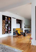 Salon moderne avec étagères en alcôve intégrées et rangement pour le bois de chauffage