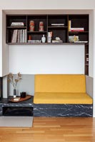 Coussin de canapé jaune sur coin salon intégré dans une alcôve avec étagères environnantes