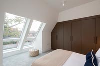 Chambre moderne avec fenêtres de toit en pente et armoire encastrée marron