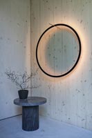 Halo circulaire noir sur mur en bois avec petite table en marbre