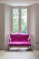 Canapé antique rose vif à côté de la fenêtre