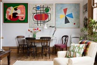 Salle à manger et mur d'œuvres d'art modernes colorées dans un espace de vie ouvert. Coussin de Nichollette Yardley-Moore www.vintagecushions.com