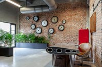 Bureau moderne et chaise avec mur de briques apparentes affichant des horloges
