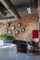 Bureau moderne et chaise avec mur de briques apparentes affichant des horloges
