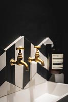 Robinets d'or au-dessus du lavabo dans la salle de bains moderne en noir et blanc