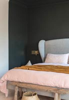 Tête de lit rembourrée dans une chambre moderne avec un mur peint en noir