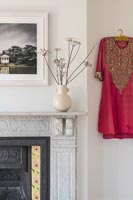 Robe de style indien rouge vif sur le mur du salon à côté de la cheminée