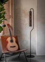 Guitare sur chaise en cuir à côté de lampadaire moderne dans le salon