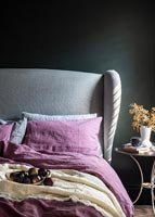 Literie rose dans une chambre moderne avec tête de lit grise et murs peints en noir