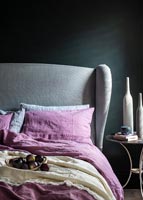Literie rose dans une chambre moderne avec tête de lit grise et murs peints en noir