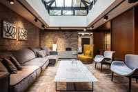 Grands canapés modulables dans un salon moderne avec des murs en briques apparentes