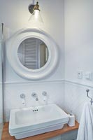 Miroir circulaire au-dessus du lavabo dans la salle de bains blanche moderne