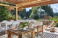 Salon extérieur et salle à manger sur la terrasse ornée de la maison de campagne en été