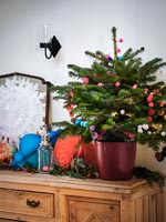 Petit arbre de Noël décoré de pompons colorés sur buffet en bois