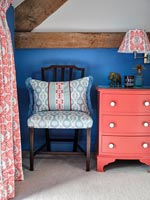 Table de chevet peinte en rose contre mur peint en bleu dans la chambre de pays