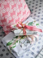 Cadeaux emballés sur le lit à côté de coussins à motifs