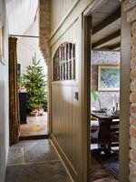 Couloir étroit menant au salon avec arbre de Noël dans maison de campagne