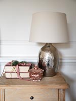 Lampe métallique sur table de chevet avec des livres emballés comme cadeau de Noël