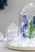 Boule à neige avec faux arbres, guirlandes lumineuses et neige en coton
