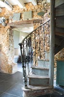 Escalier en colimaçon et mur en pierres apparentes dans le couloir de campagne