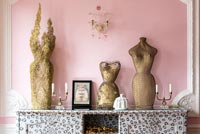 Sculptures dorées contre mur rose dans un salon éclectique