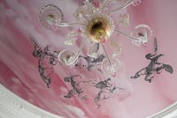 Peinture murale rose au plafond avec détail de lustre