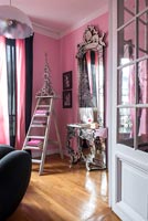Table console ornée et immense miroir dans le coin du salon peint en rose