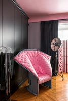 Chaise rembourrée rose moderne inhabituelle dans une chambre noire et rose