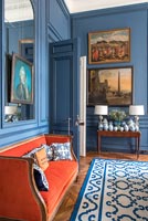 Canapé orange vif dans le salon classique peint en bleu