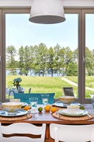 Salle à manger de campagne moderne avec vue sur la campagne du lac à travers la fenêtre