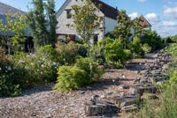 Maison de campagne et jardin avec tremplins en rondins le long du chemin de gravier