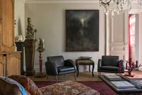 Paire de fauteuils en cuir noir sous peinture sombre dans le salon