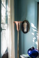 Lampadaire décoratif en cuivre et tissu photo sur mur peint en bleu