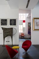 Petites chaises rouges avec table d'appoint tabouret jaune entourées d'œuvres d'art modernes
