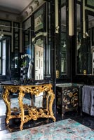 Table console dorée à côté du mur en miroir dans la luxueuse salle de bains classique
