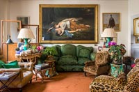 Grande peinture classique au-dessus d'un canapé en velours vert dans un salon éclectique