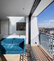 Canapé bleu dans le salon avec vue sur la ville depuis les portes coulissantes ouvertes
